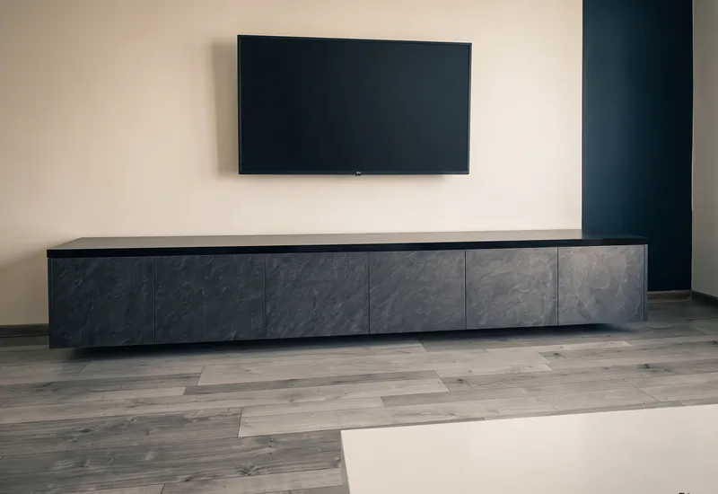 Plávajúca TV zostava v kamennom dekore v obývačke s tmavomodrou stenou