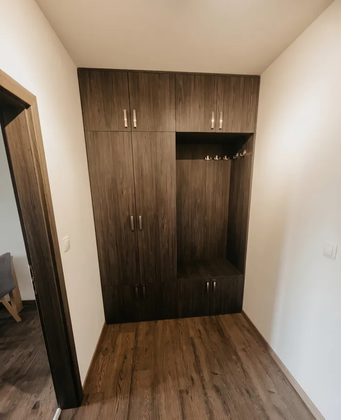 Vstavaná chodbová skriňa v tmavom dekore s nikou a nadstavcami až po strop